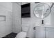 Modern bathroom with white marbled tile in the shower, a black cabinet, and a round mirror at 339 E 9Th Dr, Mesa, AZ 85210
