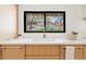 A close-up of a kitchen sink with wood cabinets and a view of the backyard garden at 4035 E Mcdonald Dr, Phoenix, AZ 85018