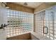 Close-up of bathroom shower featuring a glass block wall, built-in bench, and dual shower heads at 9059 E Butherus Dr, Scottsdale, AZ 85260
