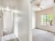 Hallway leading into carpeted bedroom with a ceiling fan and bright window overlooking leafy green foliage at 9435 S 33Rd Dr, Laveen, AZ 85339