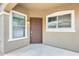 Covered front porch with a dark wood door, framed by windows and neutral stucco walls at 9435 S 33Rd Dr, Laveen, AZ 85339