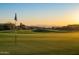 Scenic view of a golf course at sunset, showcasing a flag and distant mountains at 9726 E Hidden Green Dr, Scottsdale, AZ 85262