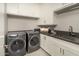 Well-equipped laundry room with front load washer and dryer, storage cabinets, and a utility sink at 9726 E Hidden Green Dr, Scottsdale, AZ 85262