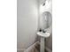 Stylish powder room featuring a pedestal sink, decorative mirror, and modern lighting at 9903 E Rotation Dr, Mesa, AZ 85212