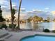 Backyard pool and landscaped yard with palm trees overlooking a tranquil waterfront at sunset, offering a serene oasis at 2545 S Gaucho --, Mesa, AZ 85202
