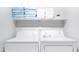 Well-lit laundry room with white washer and dryer and shelving for linens at 3907 E Marilyn Rd, Phoenix, AZ 85032