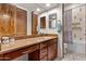 Stylish bathroom features a granite countertop, wood cabinets, and a shower with decorative tile work at 8625 E Camino Vivaz --, Scottsdale, AZ 85255