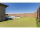 Lush backyard featuring a putting green and a pool with built in lounge chairs, surrounded by a block fence for privacy at 1644 E Joelle Dr, Casa Grande, AZ 85122
