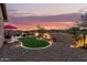 Beautiful backyard featuring desert landscaping, gravel, turf, stone, and ambient lighting at sunset at 18368 W Long Lake Rd, Goodyear, AZ 85338