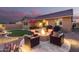 Cozy backyard with a fire pit, covered patio, grill, desert landscaping, and ambient lighting at 18368 W Long Lake Rd, Goodyear, AZ 85338
