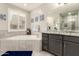 Bright bathroom featuring a soaking tub, double sink vanity, and natural light from the window at 18368 W Long Lake Rd, Goodyear, AZ 85338