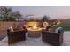 Outdoor fire pit with seating perfect for entertaining on a stone patio with ambient lighting at 18368 W Long Lake Rd, Goodyear, AZ 85338