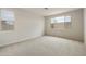 Neutral bedroom features carpeted floors, two windows, and natural light at 19039 W Rose Ln, Waddell, AZ 85355