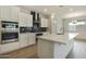 Corner view of kitchen features white cabinetry, stainless steel oven, black backsplash, and spacious island at 19039 W Rose Ln, Waddell, AZ 85355