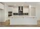 Modern kitchen featuring white cabinetry, a stainless steel range hood, and black tiled backsplash at 19039 W Rose Ln, Waddell, AZ 85355