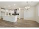 Bright kitchen with white cabinets, a dark backsplash, an island with bar seating and a modern chandelier at 19039 W Rose Ln, Waddell, AZ 85355