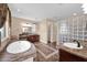 Luxurious bathroom with a soaking tub, dual vanities, and a glass block wall offering a spa-like experience at 21525 E Camacho Rd, Queen Creek, AZ 85142