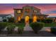 Inviting two-story home featuring a well-manicured lawn and a classic stucco exterior illuminated by a vibrant sunset at 21525 E Camacho Rd, Queen Creek, AZ 85142