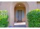 Charming front entrance framed by lush greenery and an arched doorway leading to a welcoming residence at 21525 E Camacho Rd, Queen Creek, AZ 85142