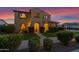 Inviting home with lush landscaping, well-lit entrance, and manicured front lawn at 21525 E Camacho Rd, Queen Creek, AZ 85142