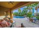 A relaxing covered patio area with comfortable seating overlooking the beautiful pool and landscaped backyard at 21525 E Camacho Rd, Queen Creek, AZ 85142