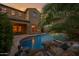 Beautiful backyard pool featuring rock waterfall, palm trees, and a covered patio at 21525 E Camacho Rd, Queen Creek, AZ 85142