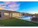 Resort-style backyard with a sparkling pool, putting green, covered patio, and serene desert views at 22884 E Via De Olivos --, Queen Creek, AZ 85142