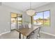 A well-lit dining room featuring a wooden table, modern light fixture, and a view of the backyard at 22884 E Via De Olivos --, Queen Creek, AZ 85142