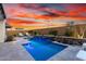 Beautiful backyard pool with waterfall feature, lush landscaping, and privacy wall at 26999 W Ponderosa Ln, Buckeye, AZ 85396