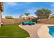 Relaxing backyard featuring a pool, seating area, and lush artificial turf at 37161 W Giallo Ln, Maricopa, AZ 85138