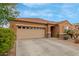 Tan home with desert landscaping, tile roof, and large driveway at 37161 W Giallo Ln, Maricopa, AZ 85138