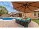 Backyard with a pool, ample seating, and an umbrella providing shade at 37161 W Giallo Ln, Maricopa, AZ 85138