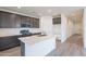 Open kitchen with gray cabinets, white countertops, stainless steel appliances, and a spacious island at 40025 W Bunker Dr, Maricopa, AZ 85138