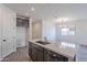 Bright kitchen with an island featuring a stainless steel sink, breakfast bar, and modern gray cabinets at 40025 W Bunker Dr, Maricopa, AZ 85138