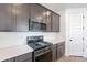 Modern kitchen features gray cabinets, stainless steel appliances, white backsplash, and sleek countertops at 40025 W Bunker Dr, Maricopa, AZ 85138