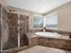 Bright bathroom featuring a tiled walk-in shower, tiled tub, and large window providing outdoor views at 4582 S Wildflower Pl, Chandler, AZ 85248