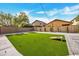 Backyard featuring an artificial turf lawn, a cornhole set, stone landscaping and mature trees at 5222 W El Cortez Trl, Phoenix, AZ 85083