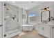 Bright bathroom featuring a glass shower, freestanding tub, and a vanity with a decorative mirror and modern fixtures at 5222 W El Cortez Trl, Phoenix, AZ 85083
