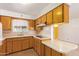 Traditional kitchen featuring honey wood cabinets, tile countertops and backsplash and a window with lace curtains at 5445 E Dallas St, Mesa, AZ 85205