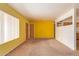 Large living room with yellow walls, neutral carpeting, and view of kitchen through the opening at 5445 E Dallas St, Mesa, AZ 85205