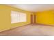 Bright living room with yellow walls, neutral carpeting, and natural light streaming through the window at 5445 E Dallas St, Mesa, AZ 85205
