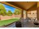 Covered patio with outdoor seating, a fire pit, and desert landscaping with lush mature trees at 6626 W Laurel Ave, Glendale, AZ 85304