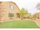 An exterior view of the home with a spacious backyard with artificial turf and a covered patio area at 6778 W Lariat Ln, Peoria, AZ 85383