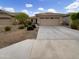 Tan single-story home featuring a two-car garage and desert landscaping at 7215 N 123Rd Dr, Glendale, AZ 85307