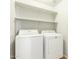 Well-lit laundry room with a full-size washer and dryer, plus built-in shelving at 7622 S 69Th Dr, Laveen, AZ 85339