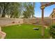 Spacious backyard with well-maintained lawn, mature trees, and cornhole boards for recreation at 7971 W Montebello Ave, Glendale, AZ 85303