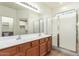 Bathroom featuring double sinks, wood cabinets, and a glass-enclosed shower for a refreshing experience at 10064 E Kilarea Ave, Mesa, AZ 85209