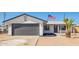 Charming single-story home featuring a gray garage door, desert landscaping, and an American flag waving proudly at 1012 E Estevan Ave, Apache Junction, AZ 85119