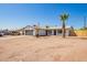 A single-story home featuring desert landscaping with multiple palm trees and an American flag on a clear, sunny day at 1012 E Estevan Ave, Apache Junction, AZ 85119