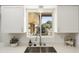 Kitchen sink area with stainless steel sink, tiled backsplash, and modern decor at 10927 W Peoria Ave, Sun City, AZ 85351